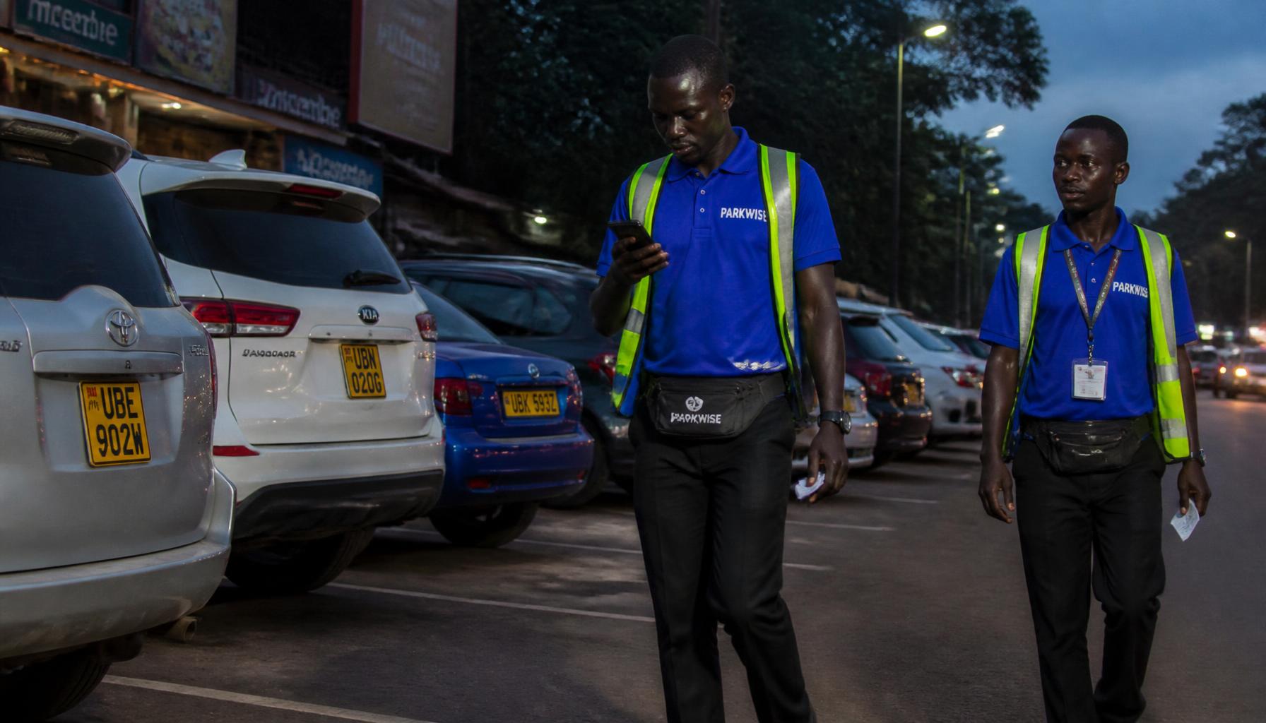 Two Parkwise attendants patrolling street parking bays at dusk